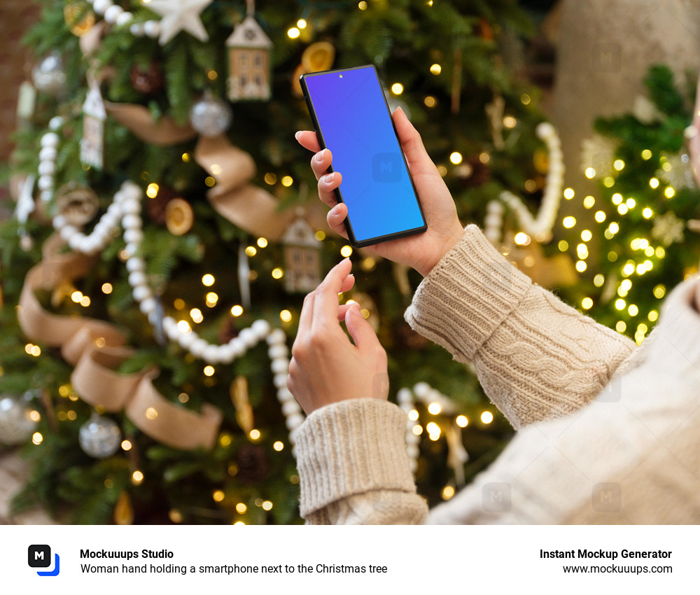 Woman hand holding a smartphone next to the Christmas tree