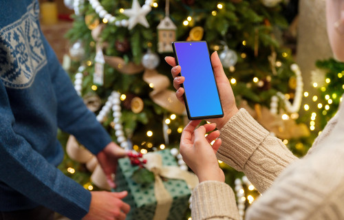 Phone mockup in hands next to the Christmas tree