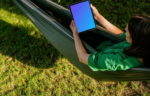 Female laying in hammock while holding a tablet