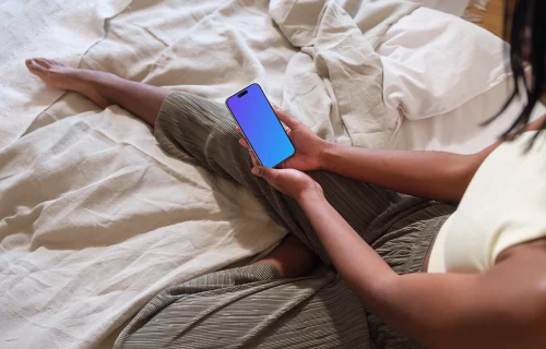 iPhone 15 Pro mockup in female hands on a cozy bed