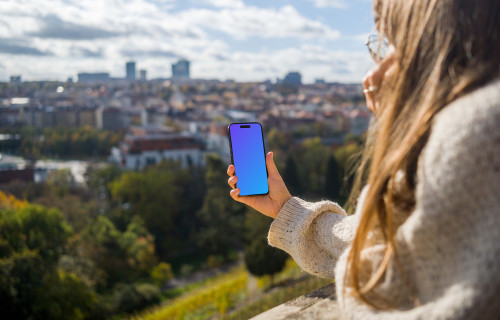 Woman hand holding an iPhone with city view mockup