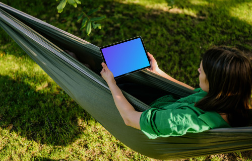 Woman laying in hammock while holding a tablet