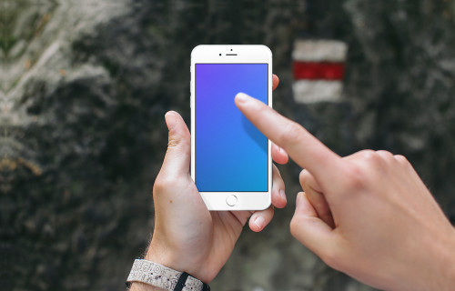 Pointage sur iPhone 6s mockup devant un panneau touristique