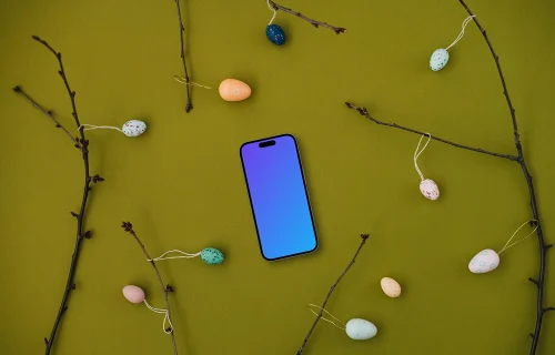 Smartphone mockup among spring branches with decorated eggs