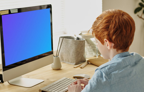 Mockup d'un enfant aux cheveux roux en train d'étudier sur un iMac