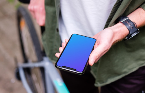 Holding an iPhone 11 Pro mockup whilst stood with a bike